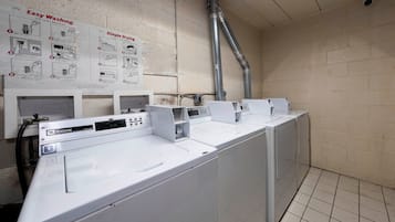 Une laverie équipée de plusieurs machines à laver et d’une affiche explicative fixée au mur.