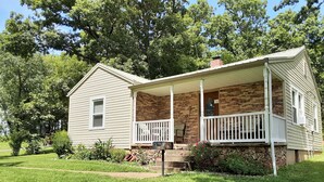 A single-story house with a porch, a brick foundation, and a well-maintained lawn. - Serene, Modern, Cottage, access to a 60 Acre Lake  (Potosi)