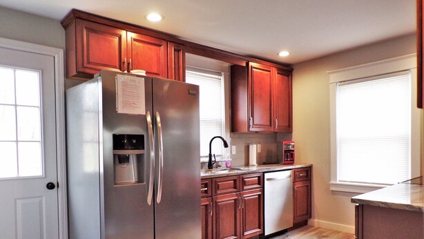 A kitchen with wooden cabinets, a stainless steel refrigerator, a microwave, and a dishwasher. - Serene, Modern, Cottage, access to a 60 Acre Lake  (Potosi)