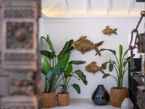 Una habitación con pared blanca, techo con tragaluz y varias plantas en macetas.