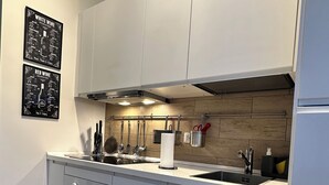 A modern kitchen with grey cabinets, a stainless steel sink, and a wooden backsplash.