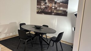 A dining area with a round table, black chairs, and a black rug.