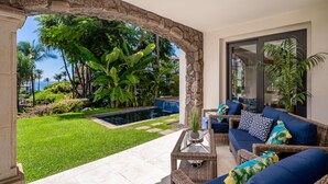 Un patio con piscina, mobiliario exterior y abundante vegetación.
