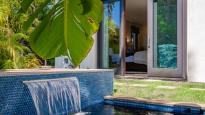 Una piscina con borde de mosaicos azules y una cascada.