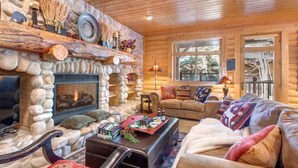 A cozy log cabin interior with a stone fireplace, wooden furniture, and a view through the windows. - Abode at Black Bear #231, private hot tub, pool & gym, Deer Valley (Park City)