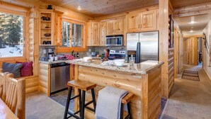 A log cabin with a kitchen featuring wooden cabinets, a granite countertop, stainless steel appliances, and a cozy seating area. - Abode at Black Bear #231, private hot tub, pool & gym, Deer Valley (Park City)