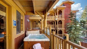 A wooden balcony with a hot tub, wooden railings, and a view of a forested area. - Abode at Black Bear #231, private hot tub, pool & gym, Deer Valley (Park City)