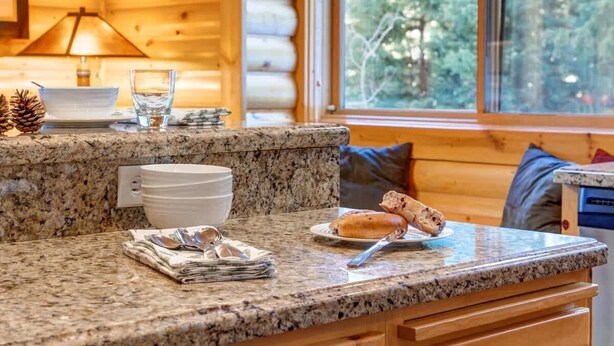 A kitchen counter with a granite top, a bowl, a glass of water, a plate with a pastry, and a stack of magazines. - Abode at Black Bear #231, private hot tub, pool & gym, Deer Valley (Park City)
