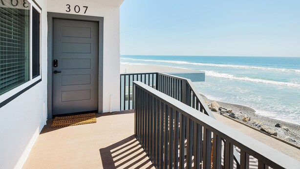 Un balcon avec vue sur l’océan, une porte portant l’inscription « 307 », et un paillasson.
