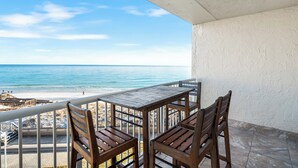 A balcony with a view of the beach and ocean.