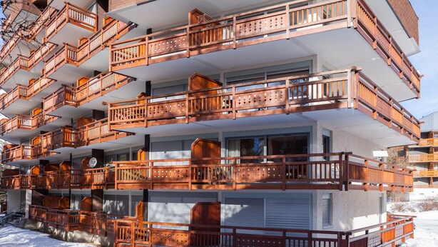 Un edificio de varios pisos con balcones de madera y ventanas grandes.