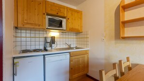 Una cocina compacta con armarios de madera, microondas, lavavajillas y un lavabo.