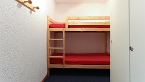 Una cama litera con colchón rojo y una escalera de madera.