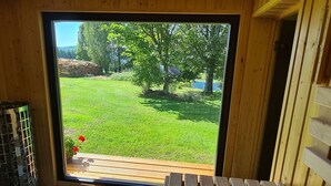 Un interior de madera con un gran ventanal corredero que da a un espacio exterior con césped.