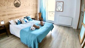 Une chambre à coucher avec une tête de lit en bois, un lit avec une literie bleue, une table de chevet avec une lampe et une fenêtre avec des rideaux.