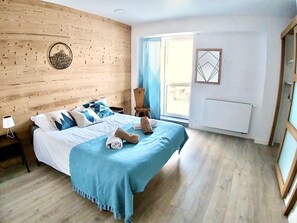 Une chambre à coucher avec une tête de lit en bois, un lit avec une literie bleue, une table de chevet avec une lampe et une fenêtre avec des rideaux.