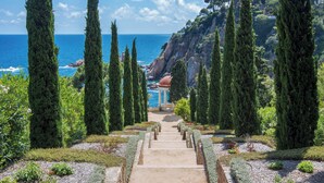 A pathway leading to a gazebo with a view of the sea and a rocky cliff.