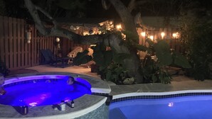 Un jardin avec un jacuzzi, une piscine et une terrasse en bois.