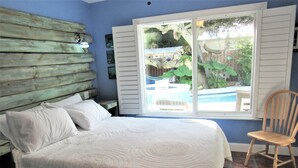Une chambre à coucher avec un lit, une chaise et une fenêtre donnant sur une piscine.