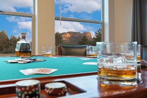 A poker table with cards and chips, a bottle of whiskey, and glasses of whiskey.