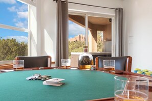 A room with a green table, poker chips, playing cards, and a bottle of whiskey.