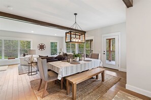 A spacious dining area with a wooden table, benches, and a hanging light fixture. - Tabor Hill House (Stowe)