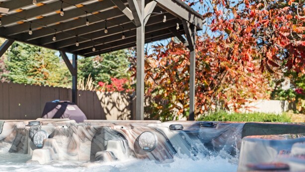 Uma banheira de hidromassagem com um deck de madeira e uma pérgola acima.