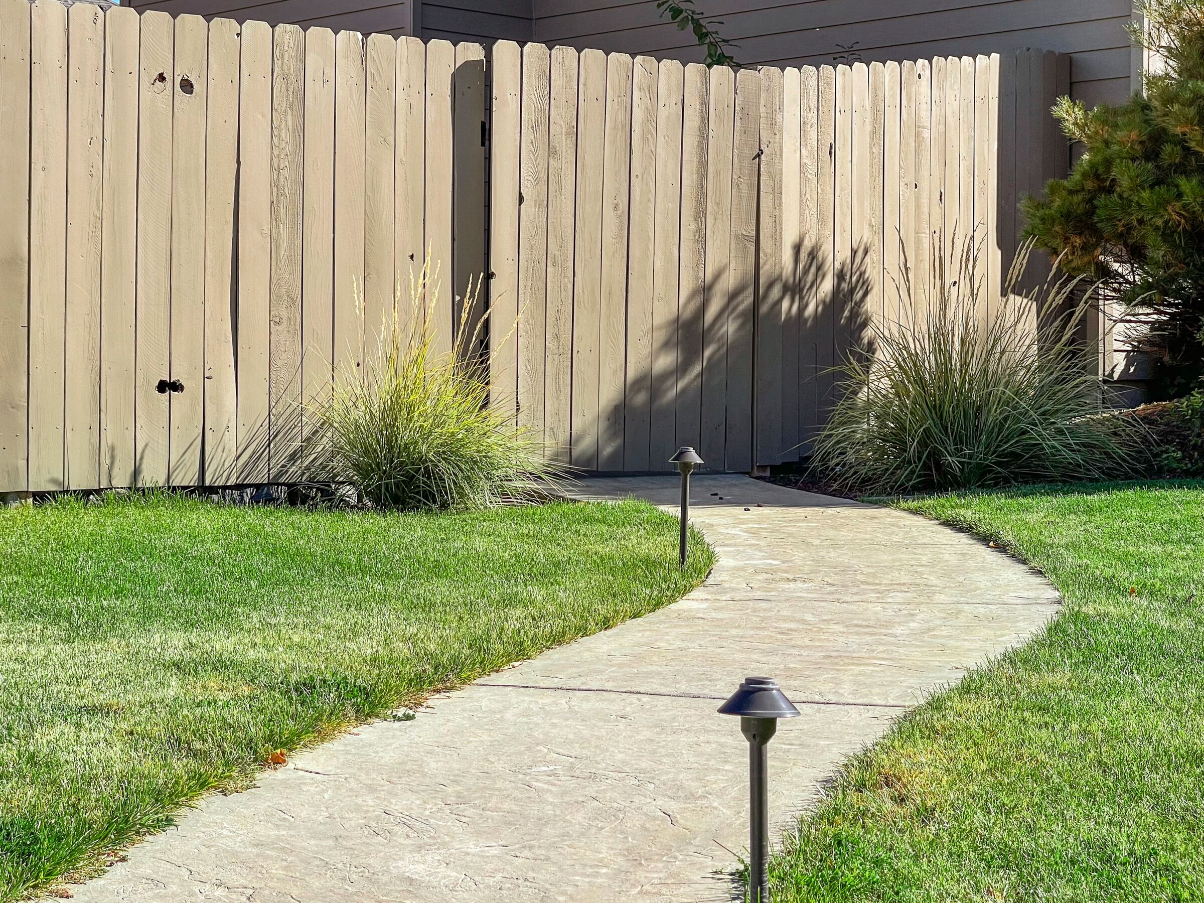 A concrete pathway leading to a wooden fence.