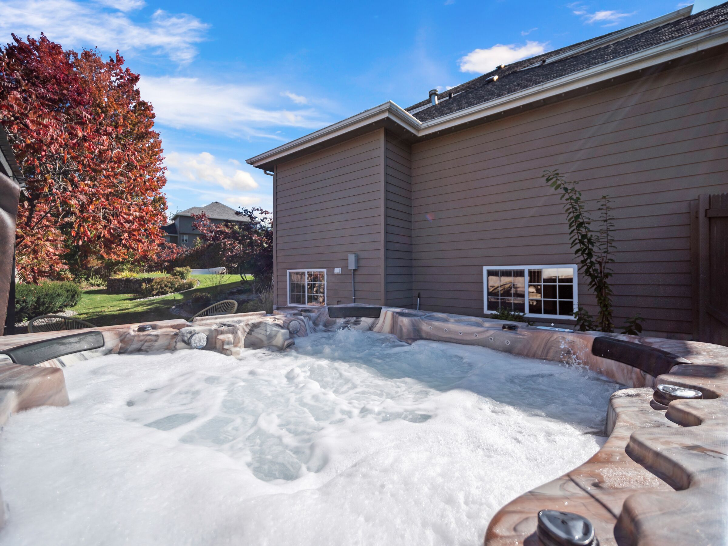 A hot tub in a backyard with a house in the background.