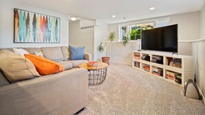 Uma sala de estar com sofá, mesa de centro, rack para TV e estante.