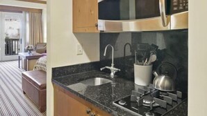 Une cuisine compacte avec des meubles en bois, un four à micro-ondes en acier inoxydable et une cuisinière à gaz.
