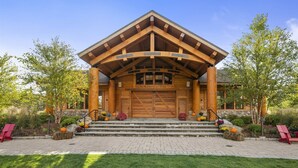 A log cabin with a large wooden entrance, stone steps, and a garden with autumn flowers. - 1228 Studio at The Lodge at Spruce Peak (Stowe)