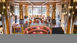 A spacious lobby with a curved red sofa, wooden beams, and multiple seating areas. - 1228 Studio at The Lodge at Spruce Peak (Stowe)