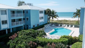 Un hotel con piscina, vistas a la playa y un edificio de dos pisos con balcones.