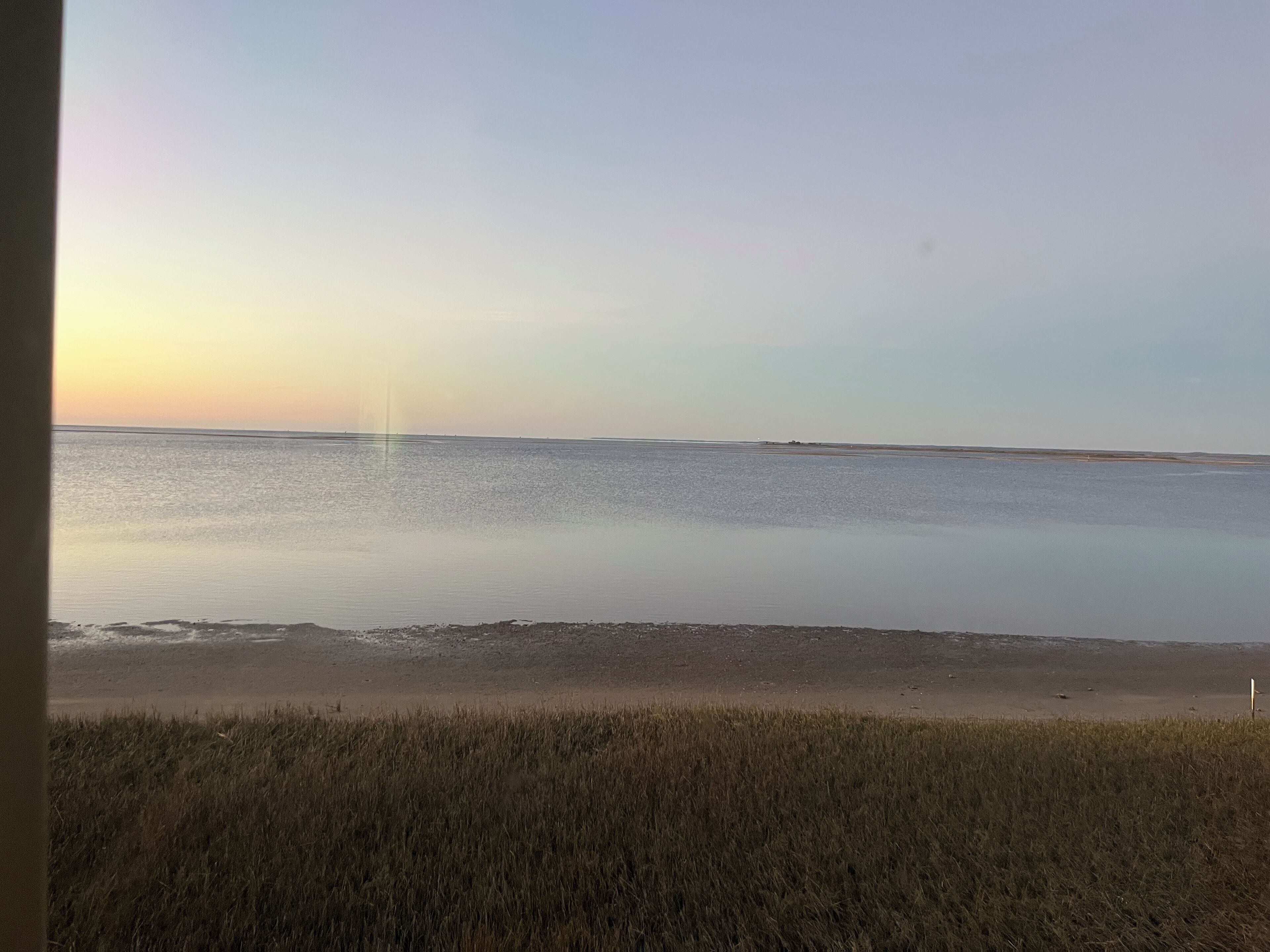 A beach with calm waters and a clear sky.