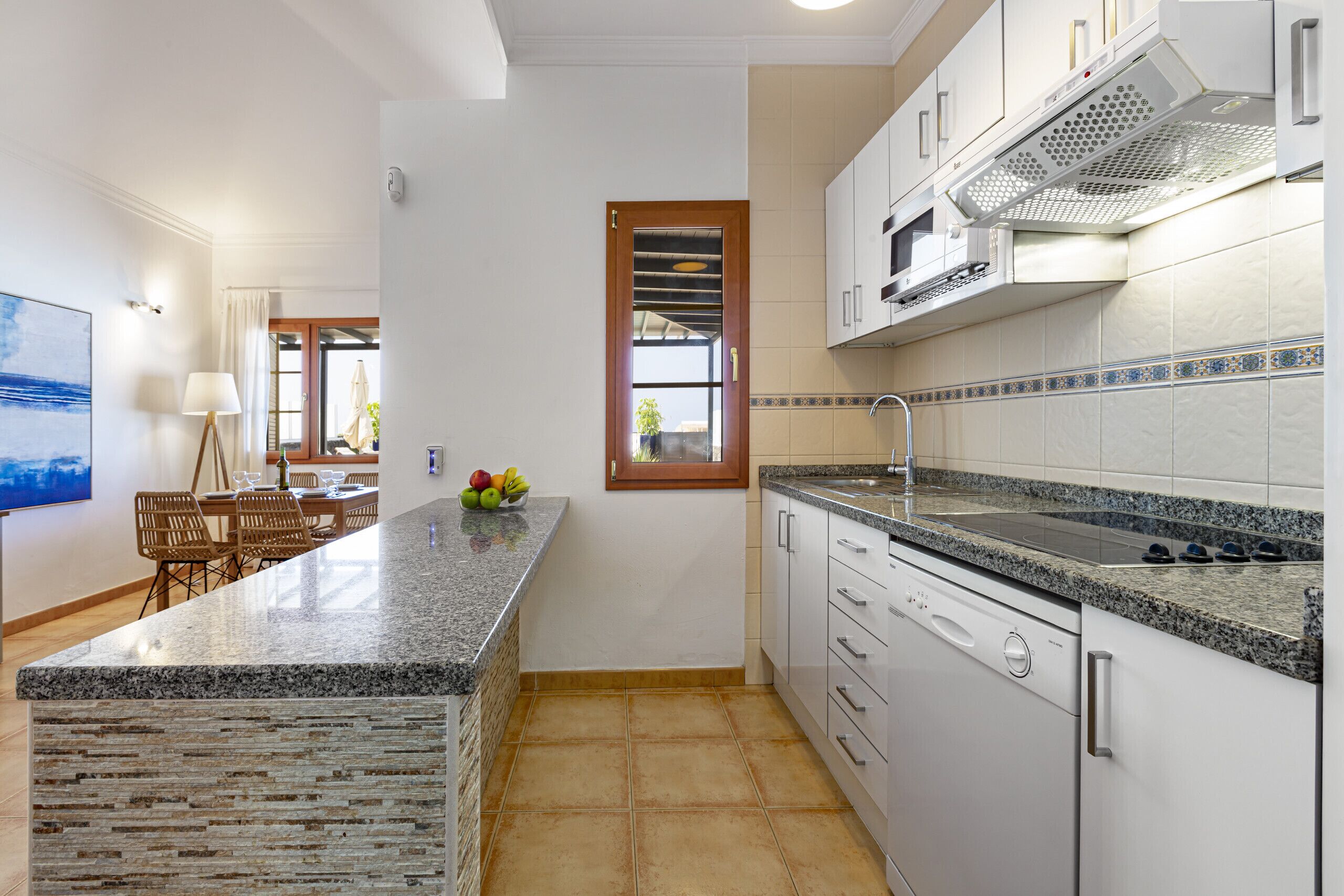 A modern kitchen with granite countertops, white cabinets, and a built-in dishwasher.