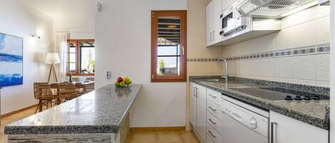 A modern kitchen with granite countertops, white cabinets, and a built-in dishwasher.