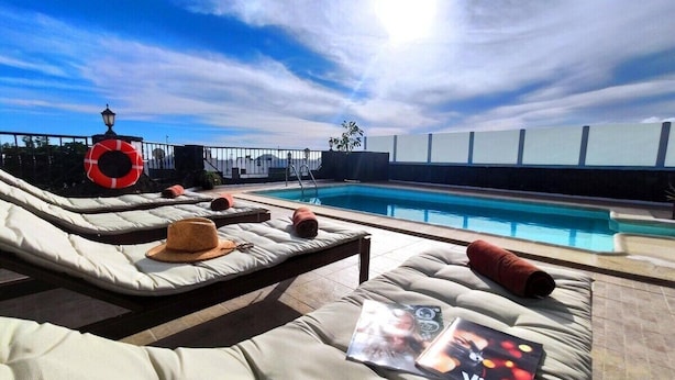 A rooftop pool area with lounge chairs, a lifebuoy, and a magazine on one of the chairs. - Villa 21, luxurious villa with heated pool (Puerto del Carmen)