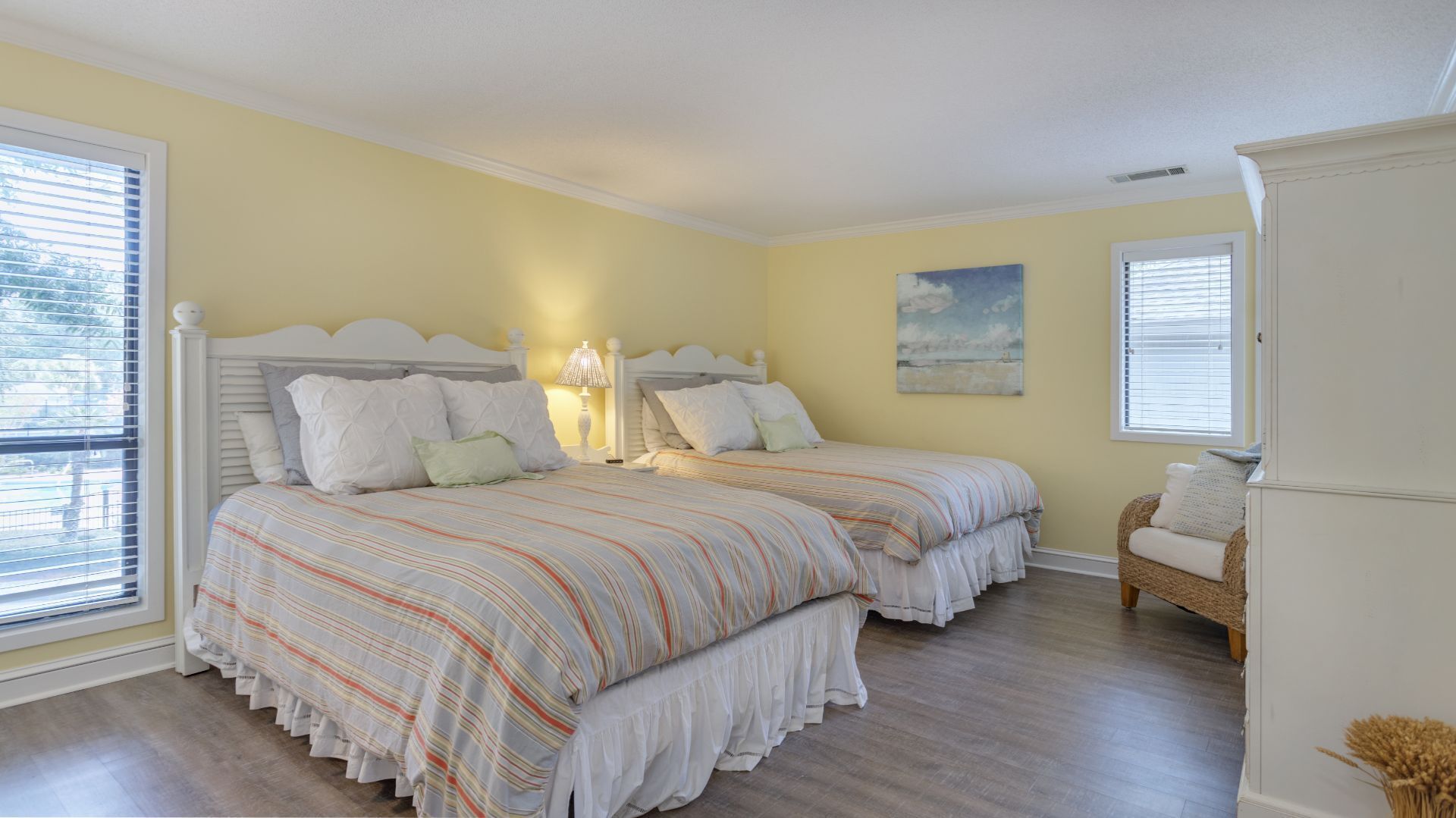 A bedroom with two beds, a chair, and a painting on the wall.