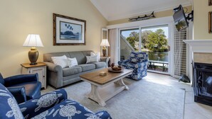 A living room with a sofa, armchair, coffee table, and fireplace.