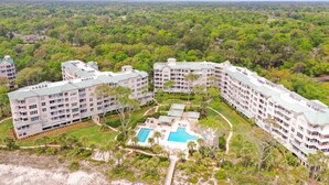 A resort with multiple buildings, a swimming pool, and surrounding greenery.