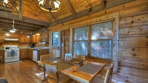 Una cabaña rústica de madera con cocina, comedor y ventanas amplias.