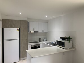 A modern kitchen with white cabinetry, a built-in oven, a microwave, and a sink.