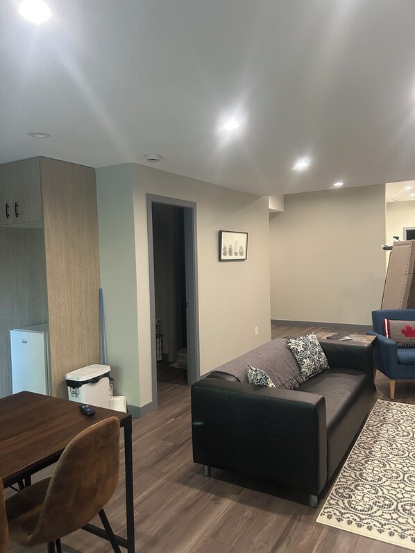 A modern living room with a dark green sofa, a wooden dining table, and a blue armchair. - Ski, golf, hike or bike right outside your door if you like! (Kimberley)