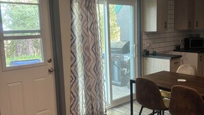 A modern kitchen with wooden cabinets, a dining table with chairs, and a sliding glass door leading to a patio area. - Ski, golf, hike or bike right outside your door if you like! (Kimberley)