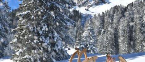 Paisaje nevado de montañas, con una silla de madera y esquíes.