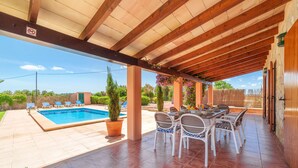 A covered outdoor area with a pool, lounge chairs, and a dining table. - Can Butxet by Interhome (Can Picafort)