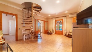 A spacious living area with a spiral staircase, a television, and a view of the outdoors. - Can Butxet by Interhome (Can Picafort)