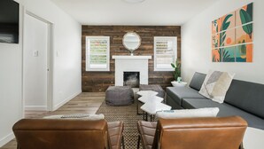 A modern living room with a fireplace, a sofa, a dining table, and leather chairs.