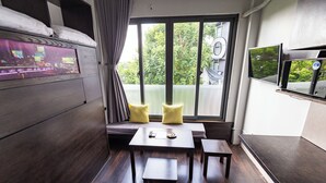 Une chambre d’hôtel moderne dotée d’une grande fenêtre, d’un téléviseur à écran plat, d’un canapé et d’une petite table.